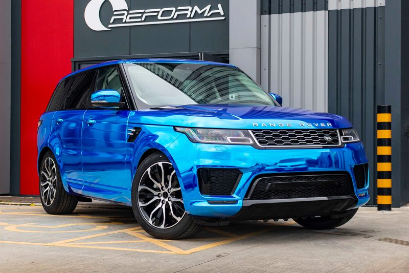 Front view of Range Rover wrapped in Chrome Blue Vinyl against the wall with Reforma logo in the background
