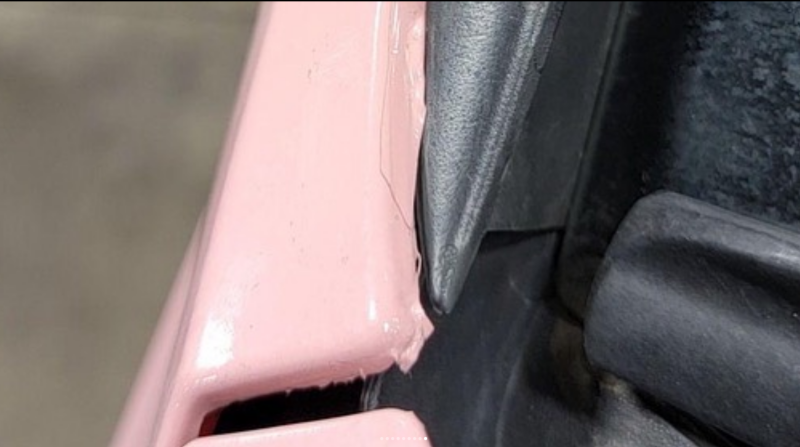 edge of car wrapped in pink vinyl showing vinyl coming off and poor quality